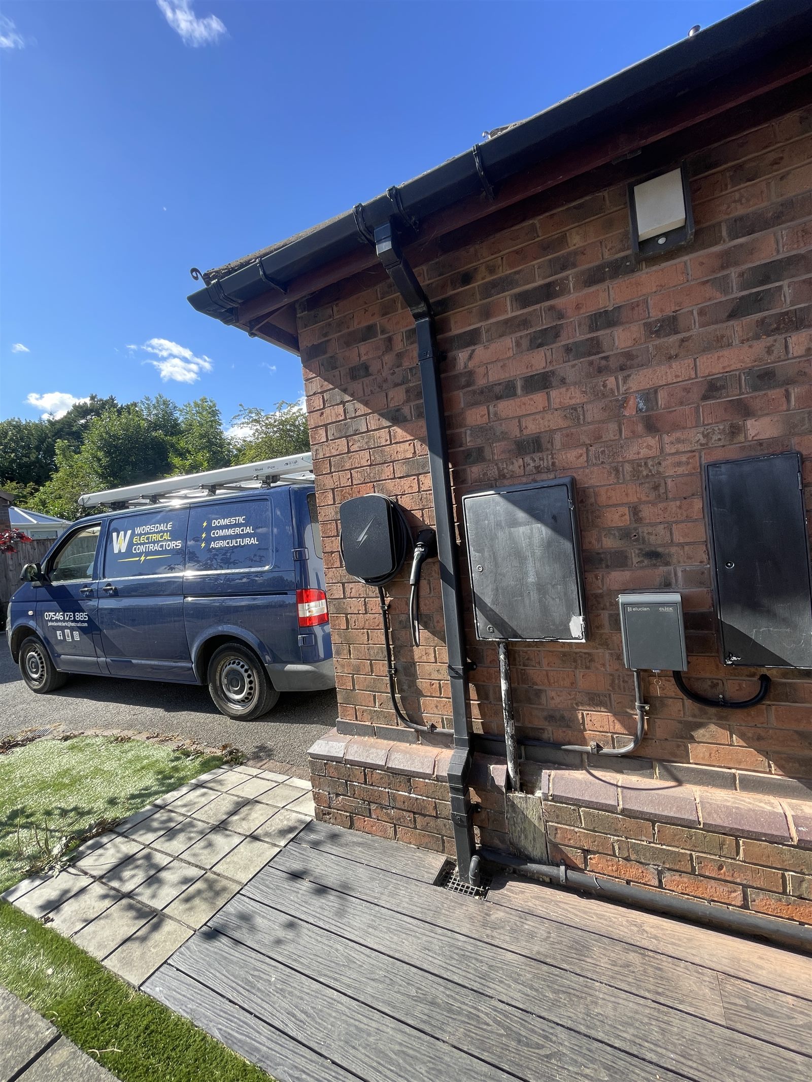 The Worsdale Electrical van parked on a driveway beside a brick house, with a wall-mounted charge point fitted next to the meter boxes.